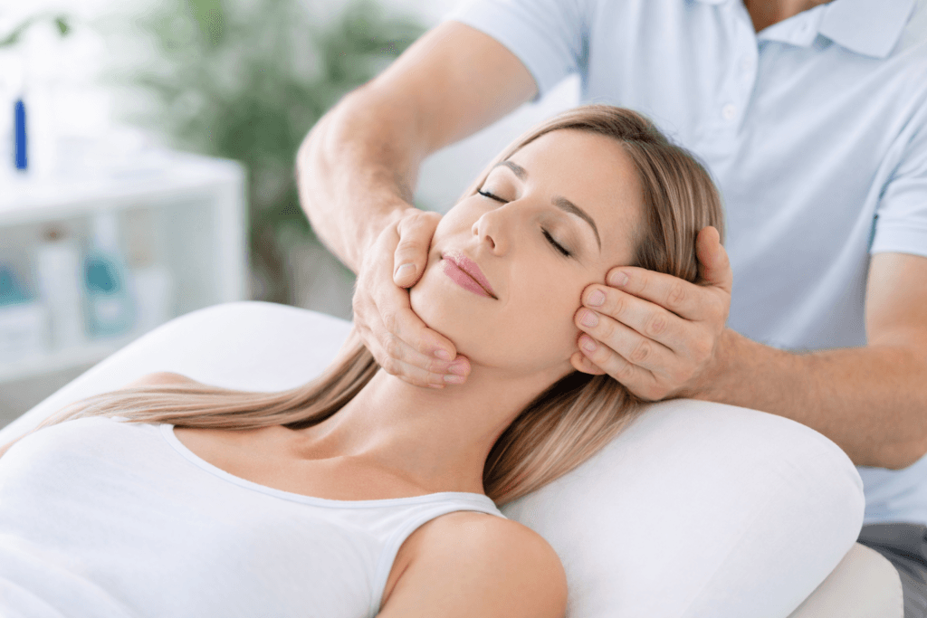 Physiotherapist performing TMJ physiotherapy treatment on patient lying on treatment table in Langley clinic